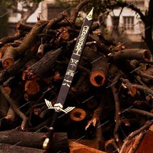 May include: A black sword with gold accents, featuring intricate designs on the blade and hilt. The sword is displayed against a backdrop of stacked logs, showcasing its detailed craftsmanship and fantasy theme.