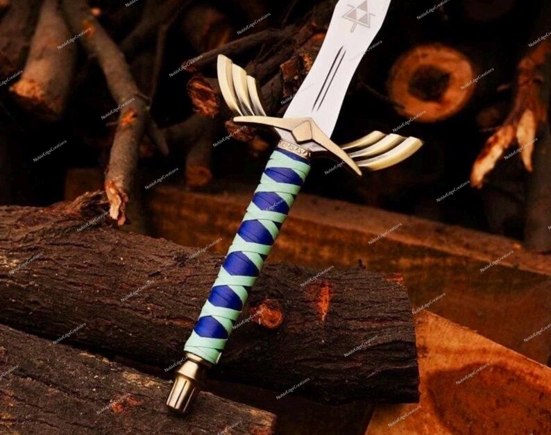 May include: A decorative sword with a silver blade and gold accents. The handle is wrapped in blue and light green material. The sword features a gold crossguard with a wing design. The blade has a triangle symbol.
