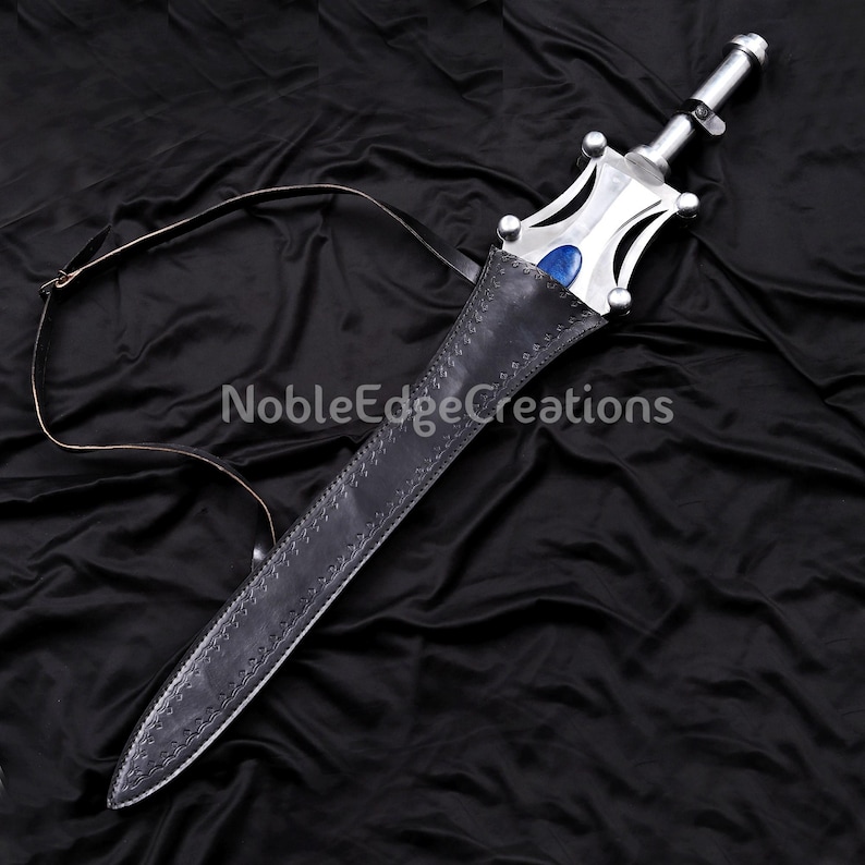 May include: A silver sword with a blue gem in the hilt, resting in a black leather sheath. The sword has a decorative handle and a leather strap. The text "NobleEdgeCreations" is visible on the background.