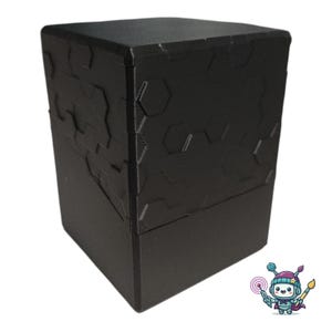Puede incluir: Una caja de almacenamiento rectangular negra que presenta una superficie texturizada con un patrón hexagonal en relieve en la parte superior y una base sólida y lisa. El recipiente tiene un diseño geométrico limpio.