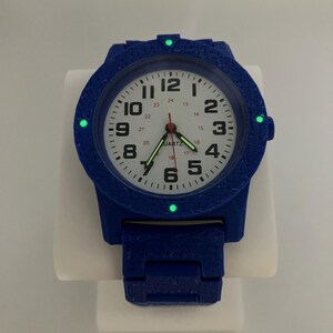 May include: A blue quartz watch with a white face, black numerals, and luminous green markers. The watch has a textured bezel and band. The watch face displays the word "QUARTZ".