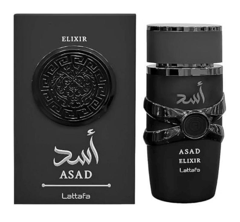 May include: A black perfume bottle and box set. The box features the word "ELIXIR" and the name "ASAD" in white script. The bottle has a decorative design and the words "ASAD ELIXIR Lattafa".