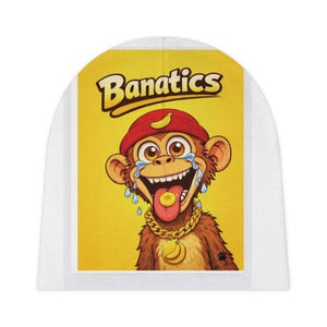 Puede incluir: Un gorro blanco con un mono de dibujos animados con gorra roja y cadena dorada. El mono tiene un plátano en la lengua y está llorando. El texto "Banatics" está en amarillo.