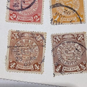 Può includere: Quattro francobolli vintage della Chinese Imperial Post con un'illustrazione centrale di un drago all'interno di una cornice circolare. I francobolli sono di colore rosso, giallo e marrone, con impresse le denominazioni di due, uno, quattro e mezzo cent.