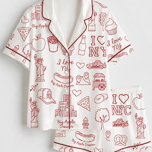 May include: A white short-sleeve button-down pajama shirt and matching shorts set featuring a red line-art print of New York City icons, including the Statue of Liberty, taxis, pizza slices, hot dogs, and the text I Love NY and Big Apple Dreams.