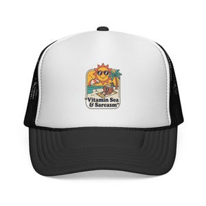 May include: Black and white trucker hat with a white front panel featuring a colorful graphic of a sun wearing sunglasses, a beach scene, and the text "Vitamin Sea & Sarcasm". The hat has a curved brim and a mesh back.