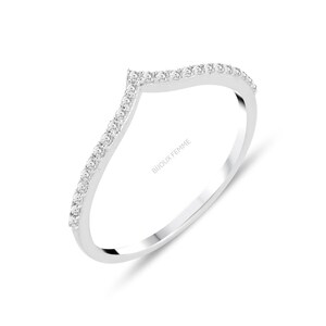 Peut inclure: Une bague argentée avec un motif en forme de chevron, ornée de petites pierres scintillantes le long du bord supérieur. Le texte "BIJOUX FEMME" est gravé sur le côté.