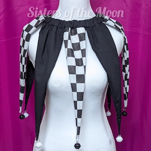 May include: A black and white checkered jester collar with long, pointed ends. The collar is black with a checkered pattern on the edges and center. Small bells hang from the tips. The text "Sisters of the Moon" is visible.