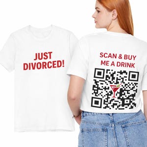 Puede incluir: Camisetas blancas con texto rojo. Una camiseta dice "JUST DIVORCED!" y la otra tiene "SCAN & BUY ME A DRINK" con un código QR y un gráfico de cóctel. Las camisetas son usadas por una persona.