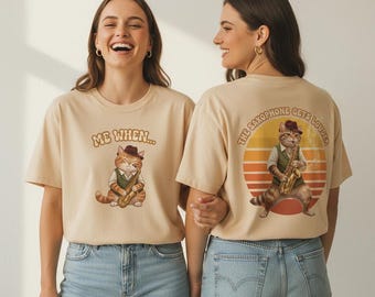 May include: Two women wearing beige t-shirts with a cat graphic. The front of the shirt says "ME WHEN..." with a cat playing a saxophone. The back of the shirt says "THE SAXOPHONE GETS LOUDER" with a cat playing a saxophone in front of a sunset.