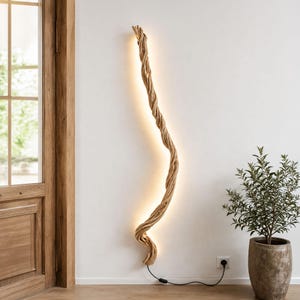Könnte beinhalten: Eine hohe, vertikale Wandleuchte aus einem einzigen, gedrehten Stück hellem Naturholz. Die Struktur verfügt über einen integrierten LED-Streifen, der ein warmes, sanftes Licht abgibt und direkt auf die Wandoberfläche strahlt.