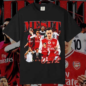 May include: Black t-shirt featuring a collage of images of a soccer player, with the name "MESUT OZIL" in red lettering. The shirt includes the Arsenal team logo and the number 10. The design has a vintage, distressed look.