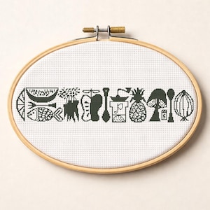 May include: Cross-stitch embroidery with dark green food icons on white fabric, set in an oval wooden hoop. The design includes a lemon slice, fish, boat, trees, a coffee grinder, pineapple, and an onion. A decorative piece for the kitchen.