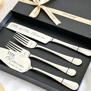 May include: A silver-toned cake serving set consisting of a serrated knife and a cake server, both featuring custom engravings. The knife is inscribed with Mr. & Mrs. Kameron, while the server displays The Kamerons and November 26, 2026.