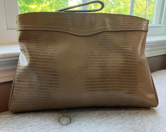 May include: A tan clutch bag with a reptile-like texture. The bag has a curved top flap and a small handle. The rectangular bag appears to be made of leather or a similar material. The bag is tan in colour.