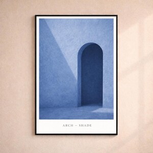 May include: A framed art print featuring a minimalist architectural design. The artwork showcases a blue archway with a shadow, set against a textured wall. The text "ARCH - SHADE" is printed at the bottom.