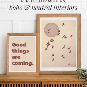 Puede incluir: Dos impresiones artísticas enmarcadas con marcos de madera. Una impresión tiene el texto "Good things are coming." en letras marrones. La otra impresión presenta un sol rosa y pájaros marrones. El texto "PERFECT FOR MODERN, boho & neutral interiors" está en la parte superior.