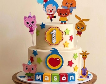 May include: A two-tier cake decorated with Plim Plim characters, colorful stars, and a large number one. The base features letter blocks spelling Mason, a heart emblem, and a giraffe figure. Toppers include a cat, pig, and balloons.