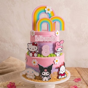 Puede incluir: Una tarta de cumpleaños de tres pisos con glaseado rosa, morado y blanco. La tarta está decorada con personajes de dibujos animados, margaritas y adornos de arcoíris. El nombre "Miranda" y el número "8" se muestran en la tarta.