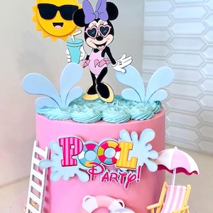 May include: A pink cake decorated with a pool party theme featuring a Minnie Mouse topper wearing heart-shaped sunglasses, a yellow sun, a white ladder, a pink and white striped beach chair, a life preserver, a beach ball, and the text Pool Party.