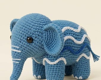 May include: A handmade blue crochet elephant with white and blue wavy accents. The elephant has large ears, a trunk, and a small tail. The eyes are black. The crochet animal is a cute and cuddly toy.