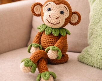 May include: A handmade crochet monkey doll with brown, tan, and green accents. The monkey has a smiling face, large ears, and a green leaf collar. Its arms and legs are also detailed with green leaves.