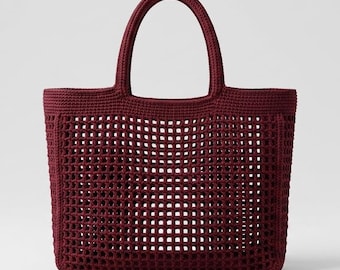 Puede incluir: Un bolso tote de color burdeos intenso elaborado con una técnica de ganchillo densa. El bolso presenta un cuerpo rectangular estructurado con un patrón de rejilla abierta en el centro y bordes de ganchillo sólido en la parte superior, los lados y la base con dos asas.