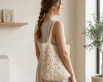 May include: A cream-colored crochet tote bag featuring a repeating fan-shaped stitch pattern. The bag has two integrated shoulder straps and a rectangular body constructed from yarn, showcasing a textured, openwork design throughout the exterior.
