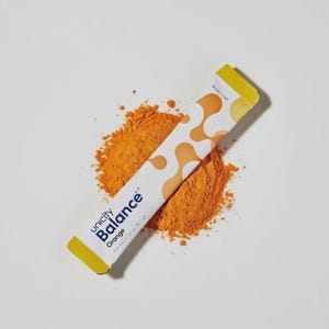 K&ouml;nnte beinhalten: Ein wei&szlig;es P&auml;ckchen Unicity Balance Orange Pulver mit gelbem Ende, das auf einem Haufen orangefarbenen Pulvers liegt. Das P&auml;ckchen hat orangefarbene abstrakte Formen und die Worte "Unicity Balance Orange".