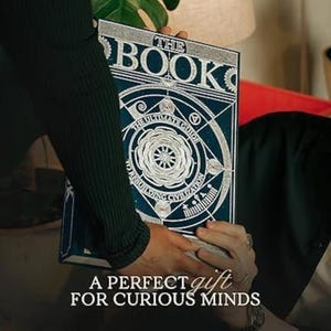 Op de afbeelding: Een witte keramische mok met een zwart handvat en de tekst "But First, Coffee" in een zwarte, handgeschreven lettertype. De mok staat op een wit oppervlak.