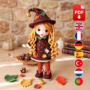 May include: A crocheted doll wearing a brown pointed hat with small pumpkin accents, a brown dress with star patterns and patches, and orange and black striped leggings. The doll has long wavy yellow hair and is surrounded by small crocheted leaves.