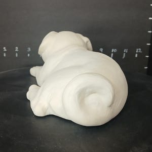 May include: White ceramic pug figurine in a curled up sleeping position.