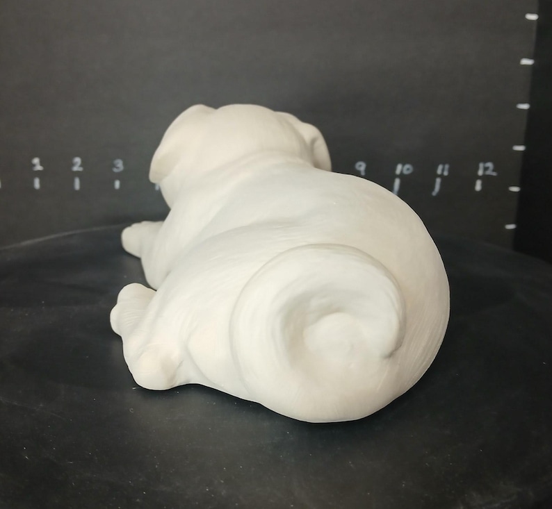 May include: White ceramic pug figurine in a curled up sleeping position.