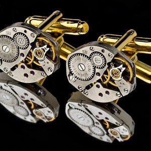 Può includere: Un paio di gemelli in oro e argento con un design steampunk. I gemelli presentano ingranaggi intricati e dettagli di orologeria.