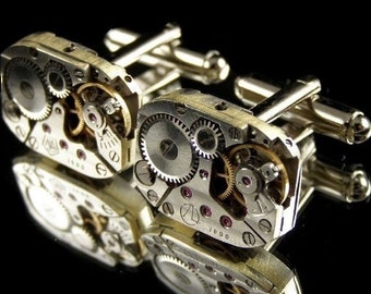 May include: A pair of silver cufflinks with intricate clockwork designs. The cufflinks are made of metal and have a polished finish. The clockwork designs are visible on both sides of the cufflinks.