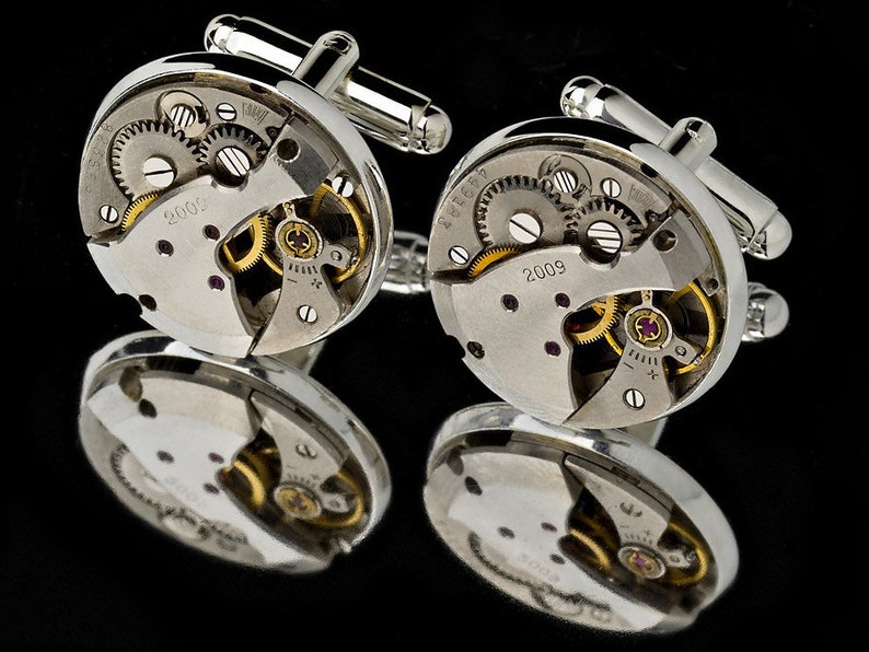 Puede incluir: Gemelos de plata con un dise&ntilde;o circular que presenta engranajes de reloj expuestos y el a&ntilde;o 2009 impreso en la cara.