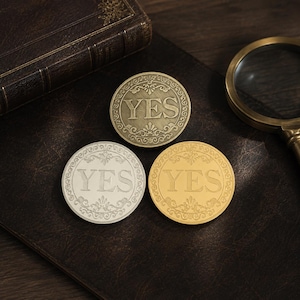 May include: Three circular metal coins featuring the word YES embossed in the center, surrounded by an ornate filigree border. One coin has an antique brass finish, one has a bright silver finish, and one has a polished gold finish.