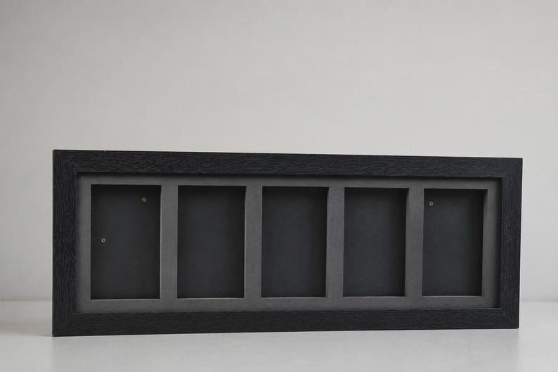 May include: A rectangular black picture frame with five openings. The frame has a dark gray interior and a textured, dark wood-like exterior. The frame is designed to hold multiple photos or artwork.
