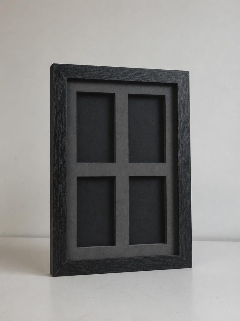 May include: A black multi-photo frame with four openings. The frame has a textured, dark gray finish and a gray matting around the photo openings. The frame is designed to hold four photos and is suitable for displaying memories or artwork.