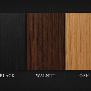May include: Three wood samples: black, walnut, and oak. The black sample has a vertical grain pattern. The walnut sample is a dark brown color. The oak sample is a light tan color. The names of the wood types are written below each sample.