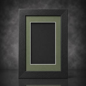 May include: A rectangular black picture frame with a green mat and white border. The frame is empty, with a black interior. The frame is made of wood and has a simple, modern design. The frame is suitable for displaying photos or artwork.