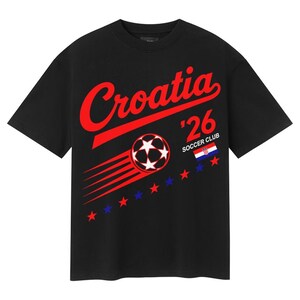 Puede incluir: Una camiseta negra de manga corta con el texto rojo Croatia, el n&uacute;mero 26 y las palabras SOCCER CLUB. En la parte delantera hay un gr&aacute;fico de un bal&oacute;n de f&uacute;tbol con l&iacute;neas de movimiento, una peque&ntilde;a bandera croata y estrellas rojas y azules.