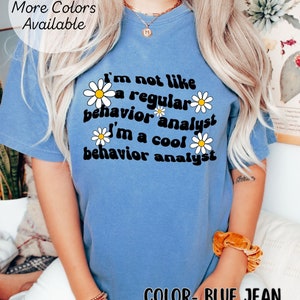 K&ouml;nnte beinhalten: Ein T-Shirt in Jeansblau mit einem wei&szlig;en G&auml;nsebl&uuml;mchen-Motiv und dem Text "Ich bin nicht wie ein normaler Verhaltensanalytiker Ich bin ein cooler Verhaltensanalytiker".