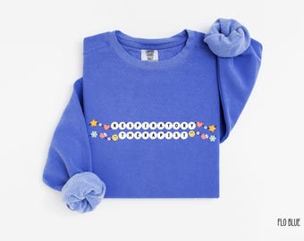 May include: A blue sweatshirt with the text "Respiratory Therapist" spelled out with white beads and colorful embellishments. The sweatshirt is a crew neck style and has a relaxed fit.