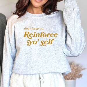 May include: A gray sweatshirt with the text "don't forget to Reinforce yo' self" in yellow.