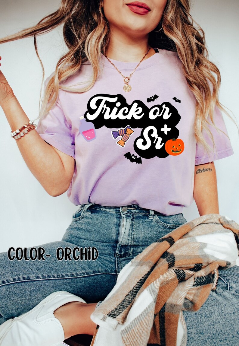Puede incluir: Una camiseta morada con el texto "Trick or Sr+" en una fuente retro. La camiseta tiene un fondo negro con un gr&aacute;fico de calabaza, caramelos y una botella de poci&oacute;n.