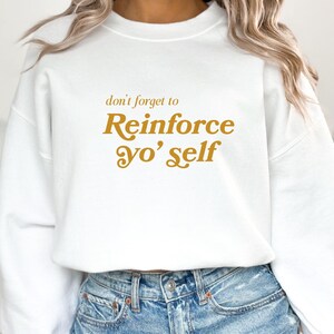 May include: White sweatshirt with a gold graphic that says "don't forget to Reinforce yo' self"