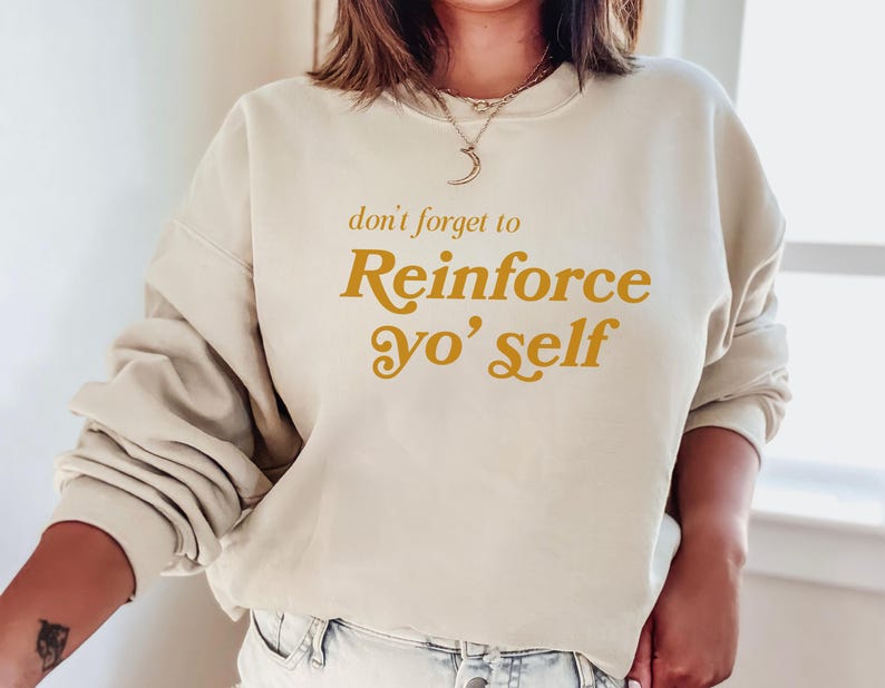 May include: A cream-colored sweatshirt with the text "don't forget to Reinforce yo' self" in a gold-colored font.