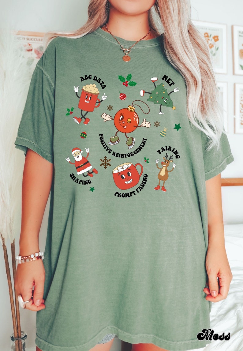 May include: Green t-shirt with a Christmas theme featuring cartoon characters and text that says "ABC Data", "Net", "Positive Reinforcement", "Pairing", "Shaping", "Prompt Fading".