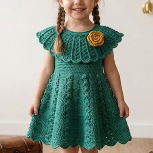 May include: A handmade, emerald green crochet dress for a child. The dress features a scalloped neckline and sleeves, with a decorative yellow flower accent. The skirt has a flared design. The dress is a charming example of handcrafted children's clothing.